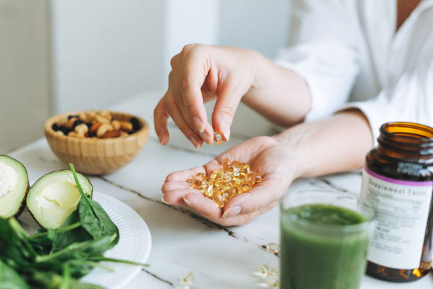 woman doctor nutritionist hands in white shirt with omega 3, vitamin d capsules with green vegan food. the doctor prescribes a prescription for medicines and vitamins at clinic, healthy food and treatment - mature woman having fish bildbanksfoton och bilder