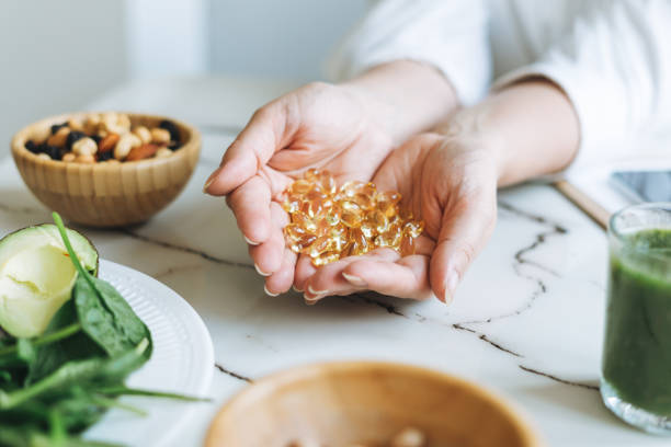 mulher médica nutricionista mãos em camisa branca com ômega 3, cápsulas de vitamina d com comida vegana verde. o médico prescreve uma prescri�ção para medicamentos e vitaminas na clínica, alimentação saudável e tratamento - capsule vitamin pill pill nutritional supplement - fotografias e filmes do acervo