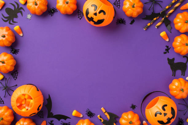 istock Top view photo of halloween decorations pumpkin baskets candy corn spiders web cat bats silhouettes and straws on isolated violet background with empty space in the middle 1341792032