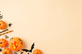 Top view photo of halloween decorations pumpkin basket candy corn straws spiders web and bats silhouettes on isolated beige background with copyspace