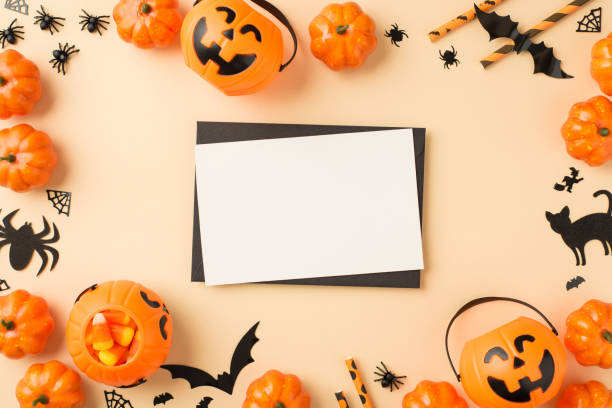 istock Top view photo of halloween decorations pumpkin baskets candy corn straws spiders cobweb bats cat silhouettes black envelope and white sheet in the middle on isolated beige background with empty space 1341792716