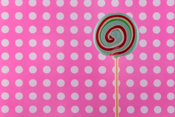 Caramel lollipop on pink white polka dots background.