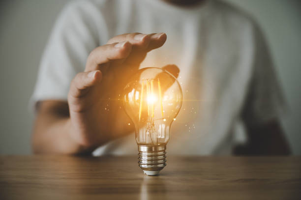 istock Hand holding light bulb on wood table. Concept of inspiration creative idea thinking and future technology innovation 1341796446