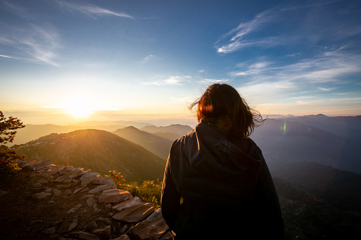 Woman enjoying the view of sunrise in the mountains.