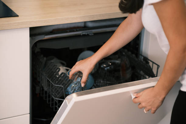 istock Woman loading the dishwasher in the kitchen at home 1341803808