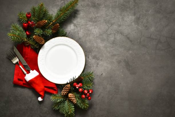 istock Christmas and New year setting table. White empty plate with cutlery and Christmas tree branches, red napkin on a gray concrete background. Card or menu template,copy space flat lay. Christmas dinner 1341804183