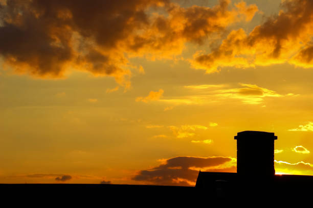 Sunset over the roof of a building with a chimney.