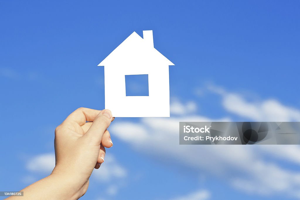 En carton maison dans la main contre le ciel bleu - Photo de Carte de crédit libre de droits