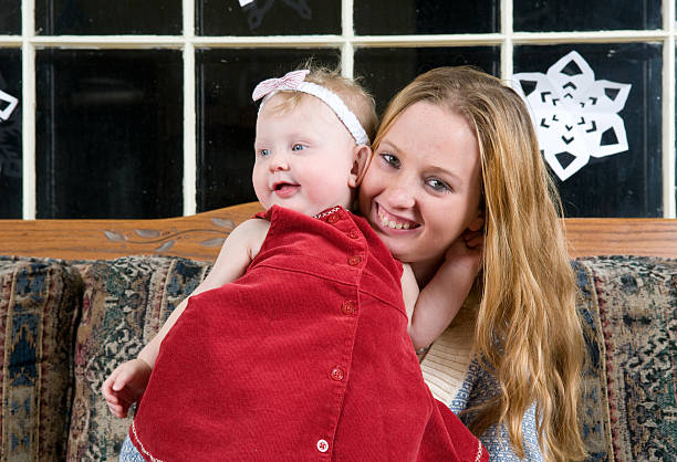 Teenage mother holding her newborn baby girl.
