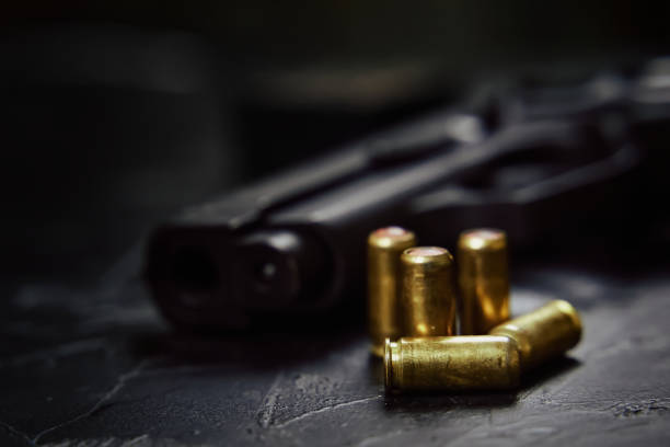 istock Pistol with cartridges on black concrete table. 1341808240