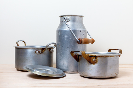 Old aluminum pots and a can on the kitchen shelf. Vintage tableware in still life.