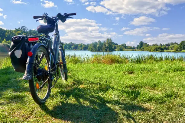 Packed touring bike on a meadow in front of a pond during a bike tour through Germany