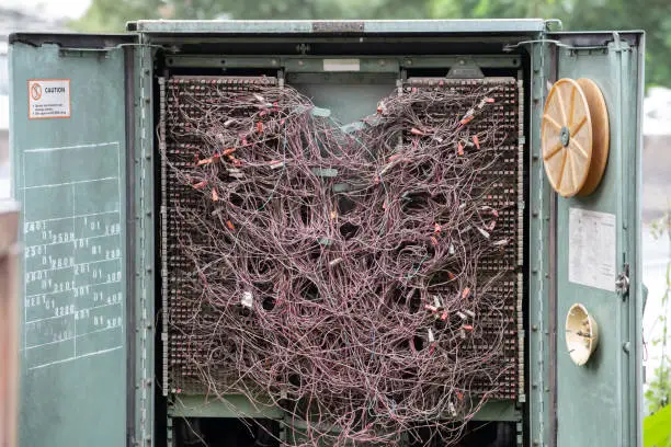 Photo of messi telephone lines wires in the steel cabinet.