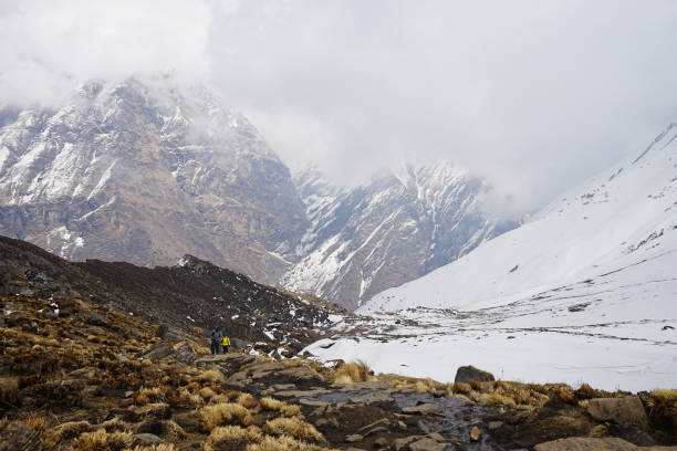 istock Rocky trail pathway among snowy mountain view with cloudy blue sky 1341812626