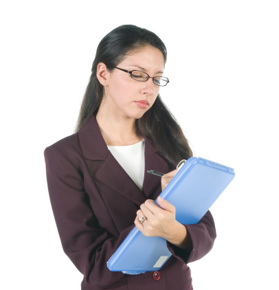 A young businesswoman writing on a clipboard.