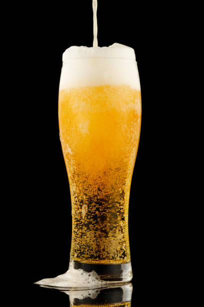 istock Light yellow beer with foam in a glass black background 1341815998