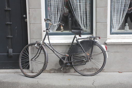 an old black bicycle parked on a wall with a window
