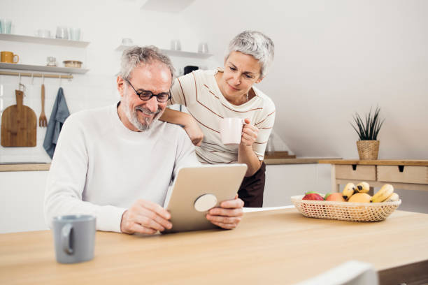 istock Happy senior couple enjoying coffee and using tablet at home 1341820983