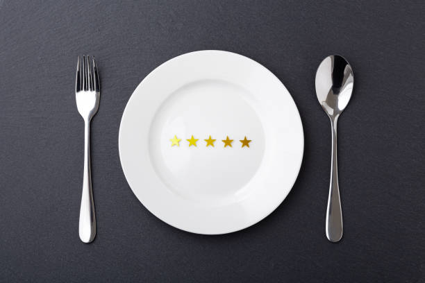 istock Five gold star on white plate with fork and spoon on black stone background 1341821731