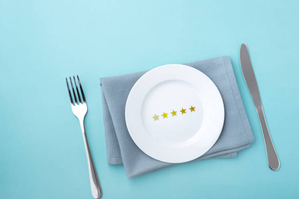 istock Five stars on white plate with fork and knife on blue background 1341821744