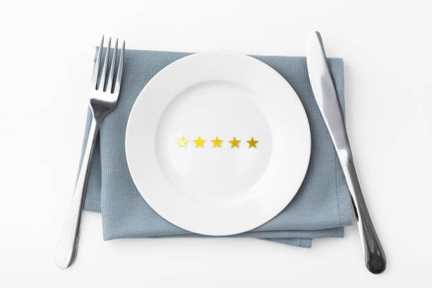 istock Five gold stars on white plate with fork and knife isolated on white background 1341821748