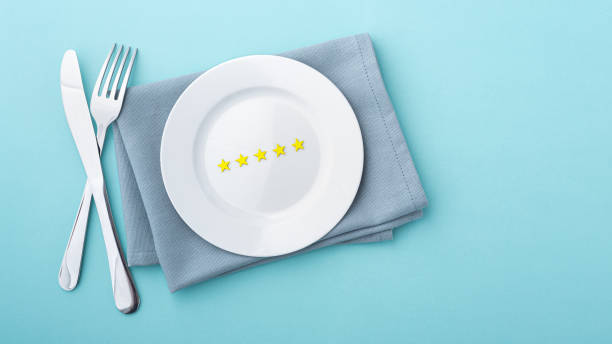 Gold stars on white plate with fork and knife on blue background