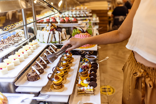 Woman Picking up cake at buffet in hotel