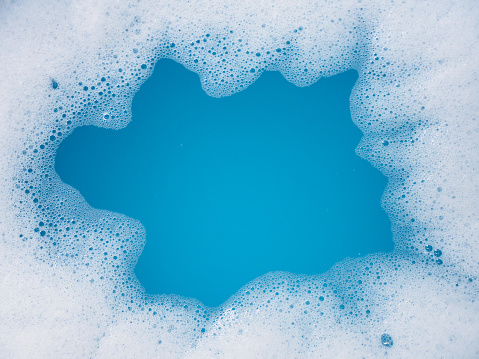 Top view of frame made of detergent foam bubble in blue basin.