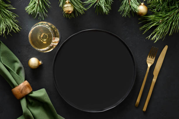 Christmas table setting with golden decoration, cutlery and gold decorations on black background. Christmas empty table setting with sparkling wine, golden cutlery and festive decorations on black background with copy space. Top view. Xmas or New Year holiday party. restaurant table layout stock pictures, royalty-free photos & images