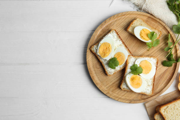 istock Tasty sandwiches with boiled eggs served on white wooden table, flat lay. Space for text 1341826682