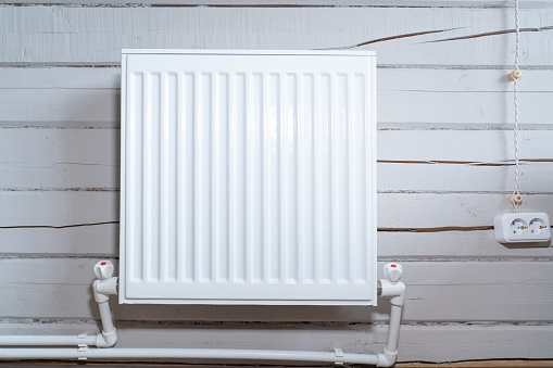 White radiator for heating on a wooden wall made of timber
