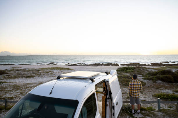 istock Man stands next to camper van with solar panel looking out to horizon 1341829445