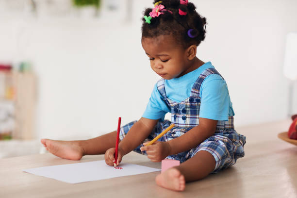 mignon tout-petit fille dessinant avec des crayons en utilisant les deux mains - left handed photos et images de collection