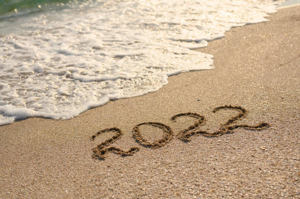 istock Sandy beach, sea wave and the inscription 2022. 1341832600