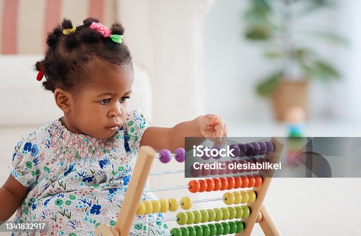 istock cute african american baby girl playing colorful abacus toy at home 1341832917