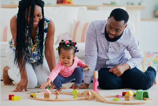 happy family with toddler baby playing toy railway together at home