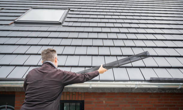 man puts a gutter mesh to the rain gutter to protect the gutter from leaves. - çatı oluğu stok fotoğraflar ve resimler