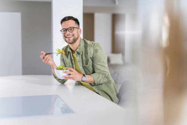 istock Young man eating a salad at home. 1341836735