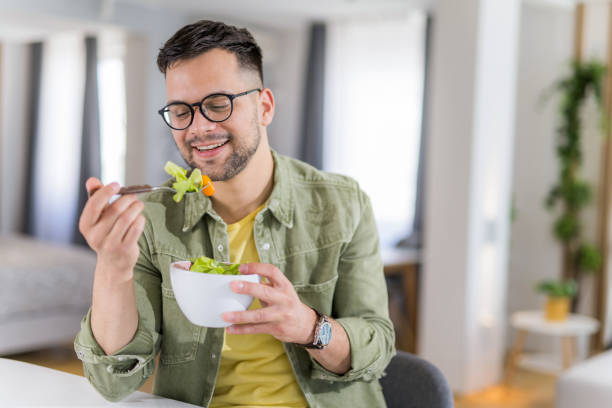 istock Young man eating a salad at home. 1341836758