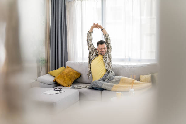 istock Happy young man waking up rejuvenated after a nice nap on sofa. 1341837400