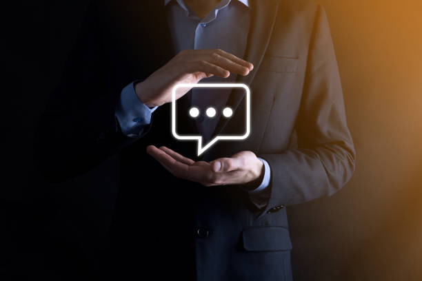 istock Businessman holding a message icon, bubble talk notification sign in his hands. Chat icon, sms icon, comments icon, speech bubbles 1341837429
