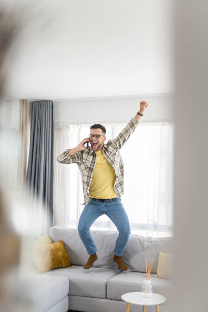 istock Ecstatic young man hearing wonderful news while talking on phone at home. 1341838524