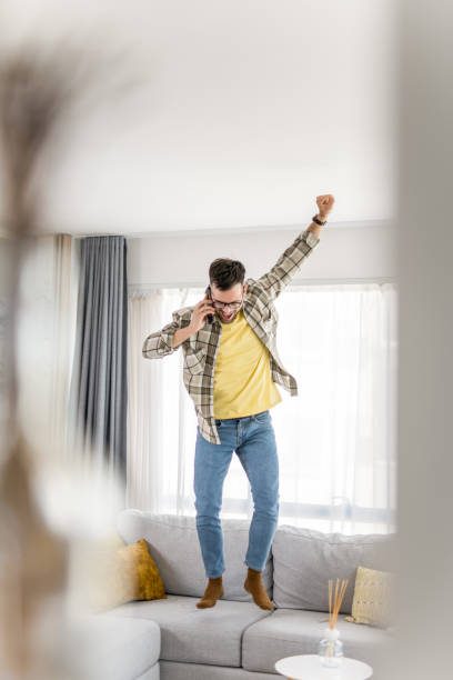 istock Ecstatic young man hearing wonderful news while talking on phone at home. 1341838553