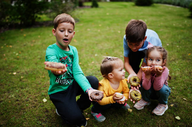 quattro bambini con ciambelle nel cortile serale - 12 23 mesi foto e immagini stock