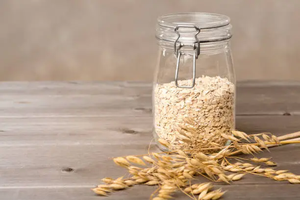 cereals in jar, oat plant on wood table