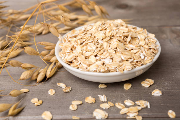 oat flakes in bowl and plant, wodden background stock photo