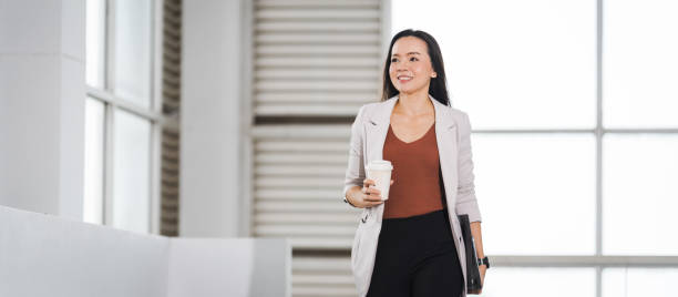 Businesswoman Holds Take Away Coffee Cup Stands in Company Building stock photo