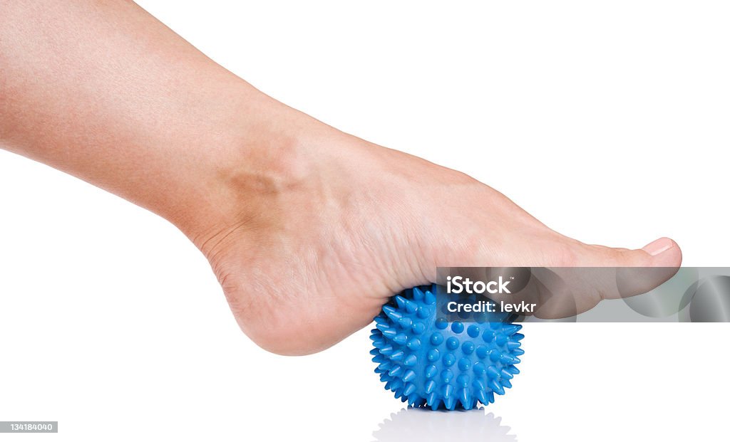 Woman's foot with massage ball Woman's foot with spiny plastic blue massage ball isolated on white background Sole Of Foot Stock Photo