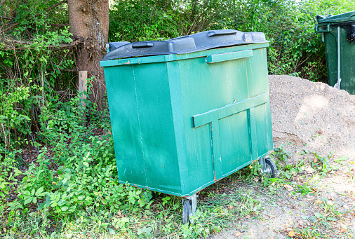 Green plastic garbage container at the outdoors in sunny day