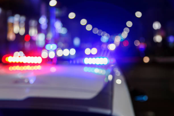 defocused photo of police car lights in night city with selective focus and bokeh defocused photo of police car lights at night in city with selective focus and blurry car traffic in the bokeh police vehicle lighting photos stock pictures, royalty-free photos & images